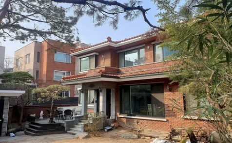 논스 오호라 외관 — 나무에 둘러싸인 붉은 벽돌 2층 주택
